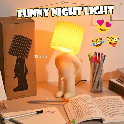 Humorous night lamp with a lampshade head on a desk with books and pens.