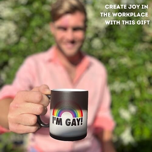 Person holding a rainbow 'I'm Gay!' mug with blurred background